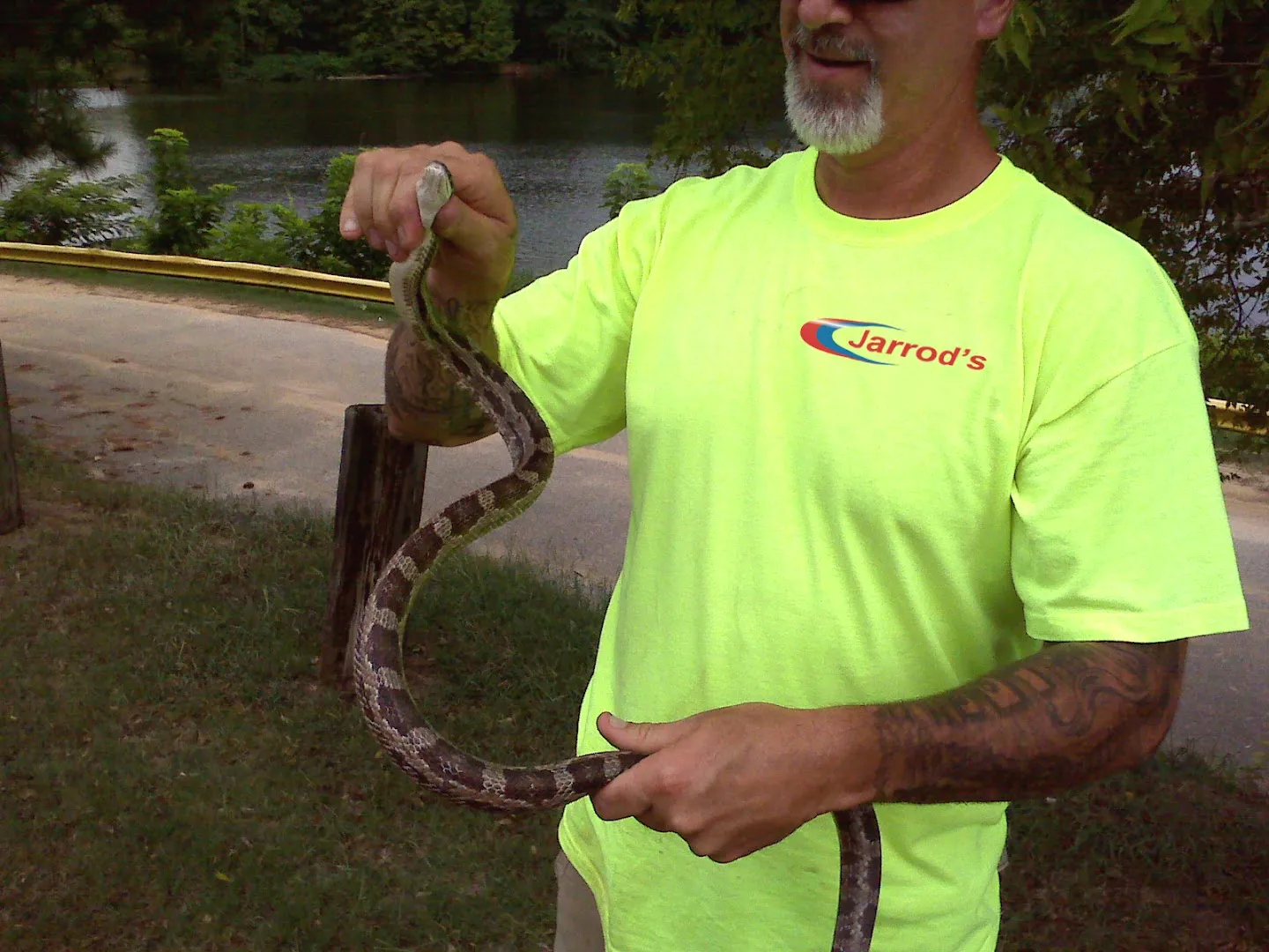 Snake Removal in Columbus, GA: Jarrod's technician holding a large snake removed from a property near a lake